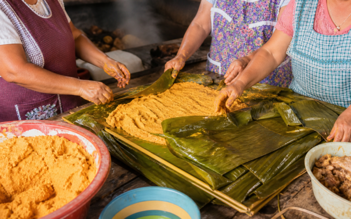Cocineras tradicionales de la Huasteca sirviendo zacahuil envuelto en hojas sobre una mesa comunitaria